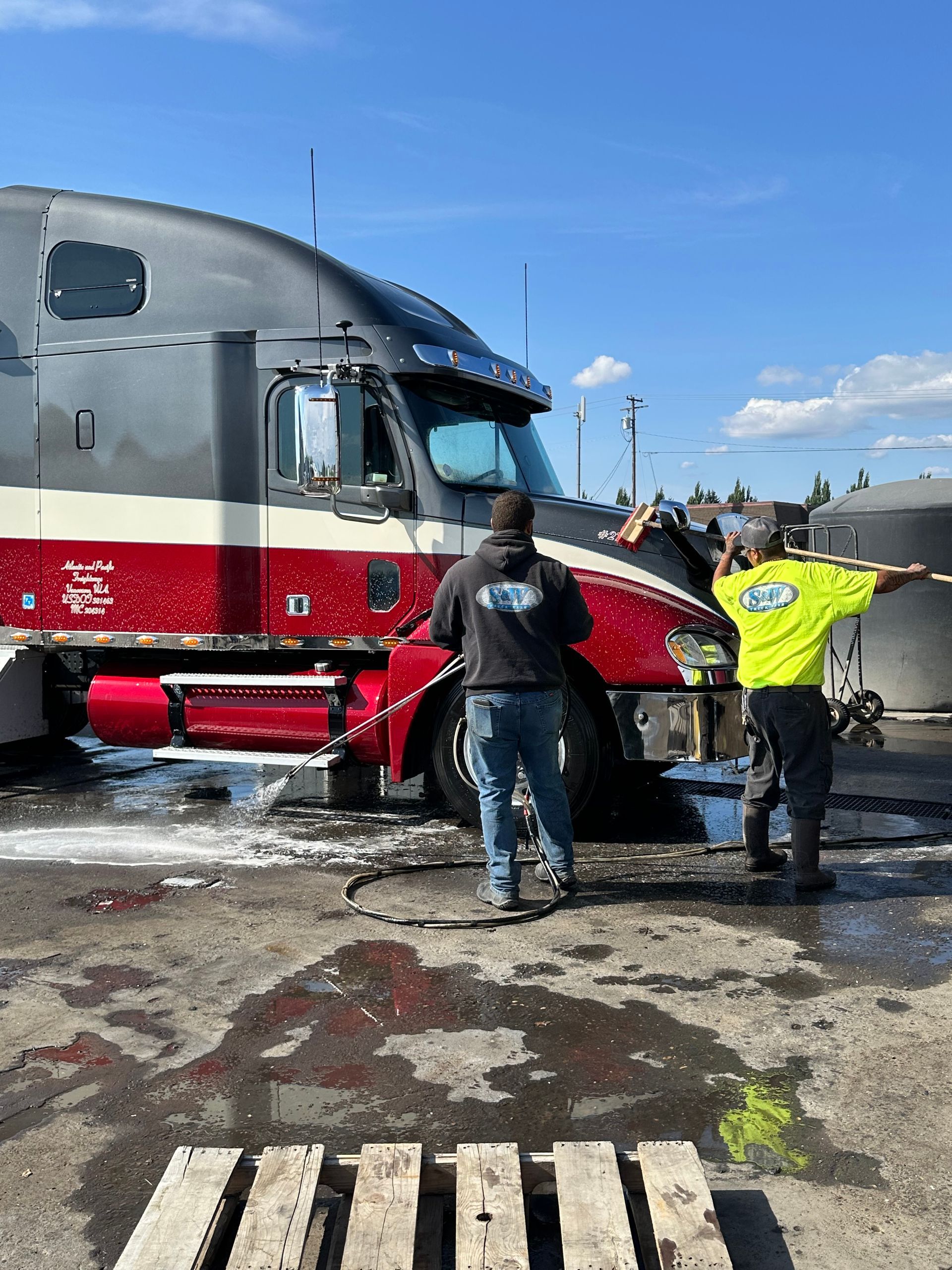 White truck being power washed outdoors; streaks of dirt are visible on the side.