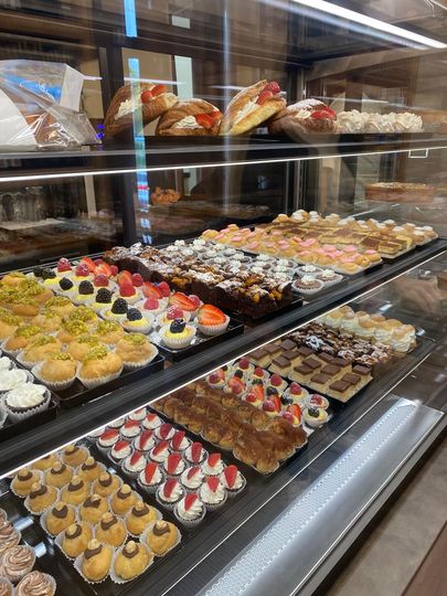 Pasticcini in vetrina: torte, crostate e dessert ripieni di crema con guarnizioni di frutta colorata.