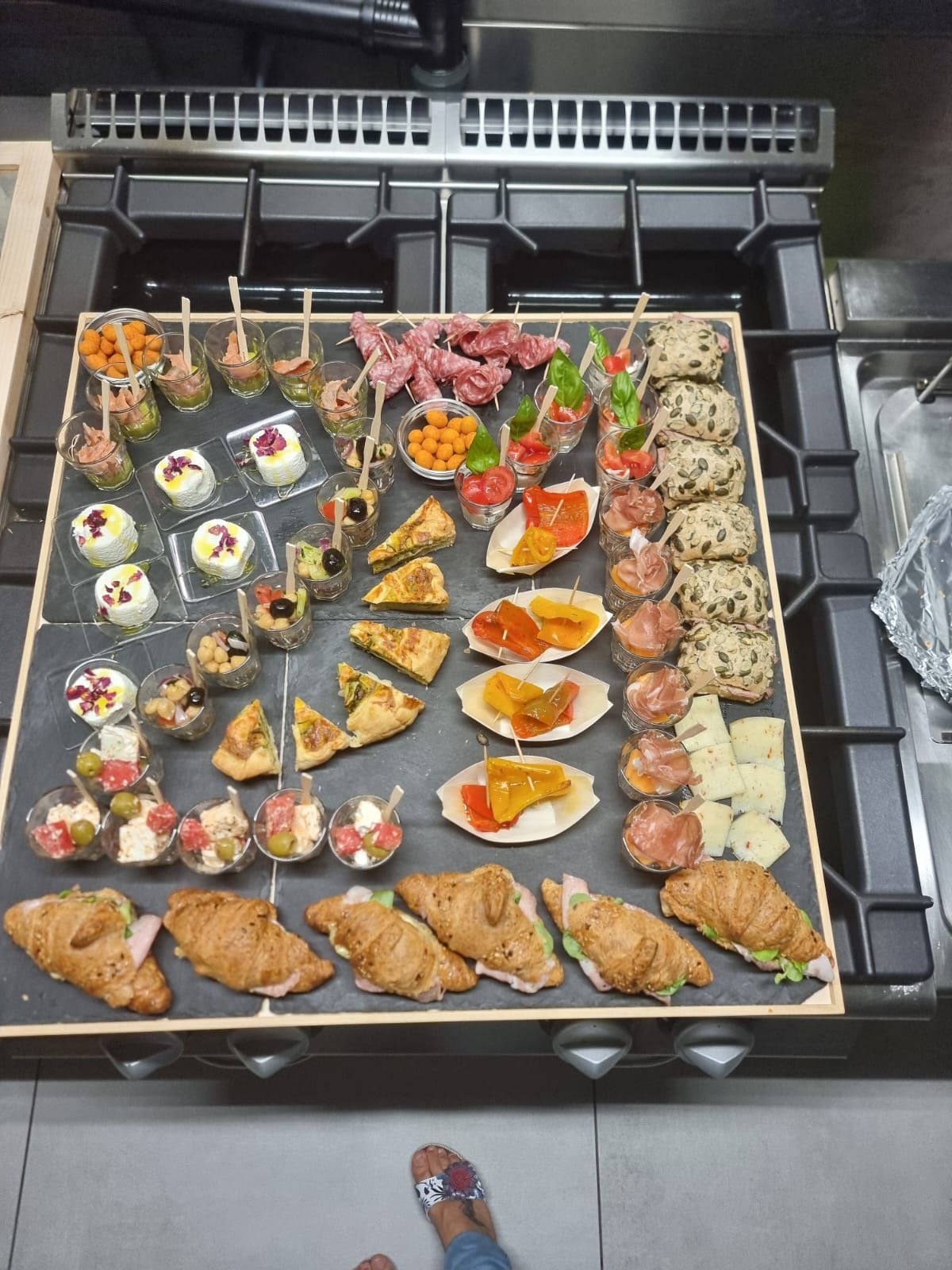 Un piatto di antipasti sul fornello. Include mini croissant, insalate e altri piccoli stuzzichini.