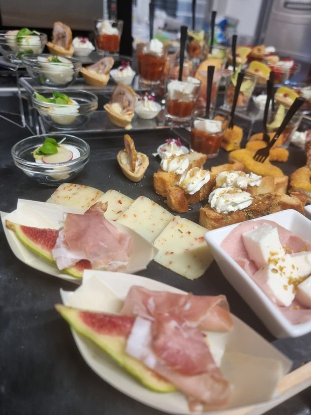 Antipasti assortiti su vassoi, tra cui prosciutto, fichi, formaggio e crostini.
