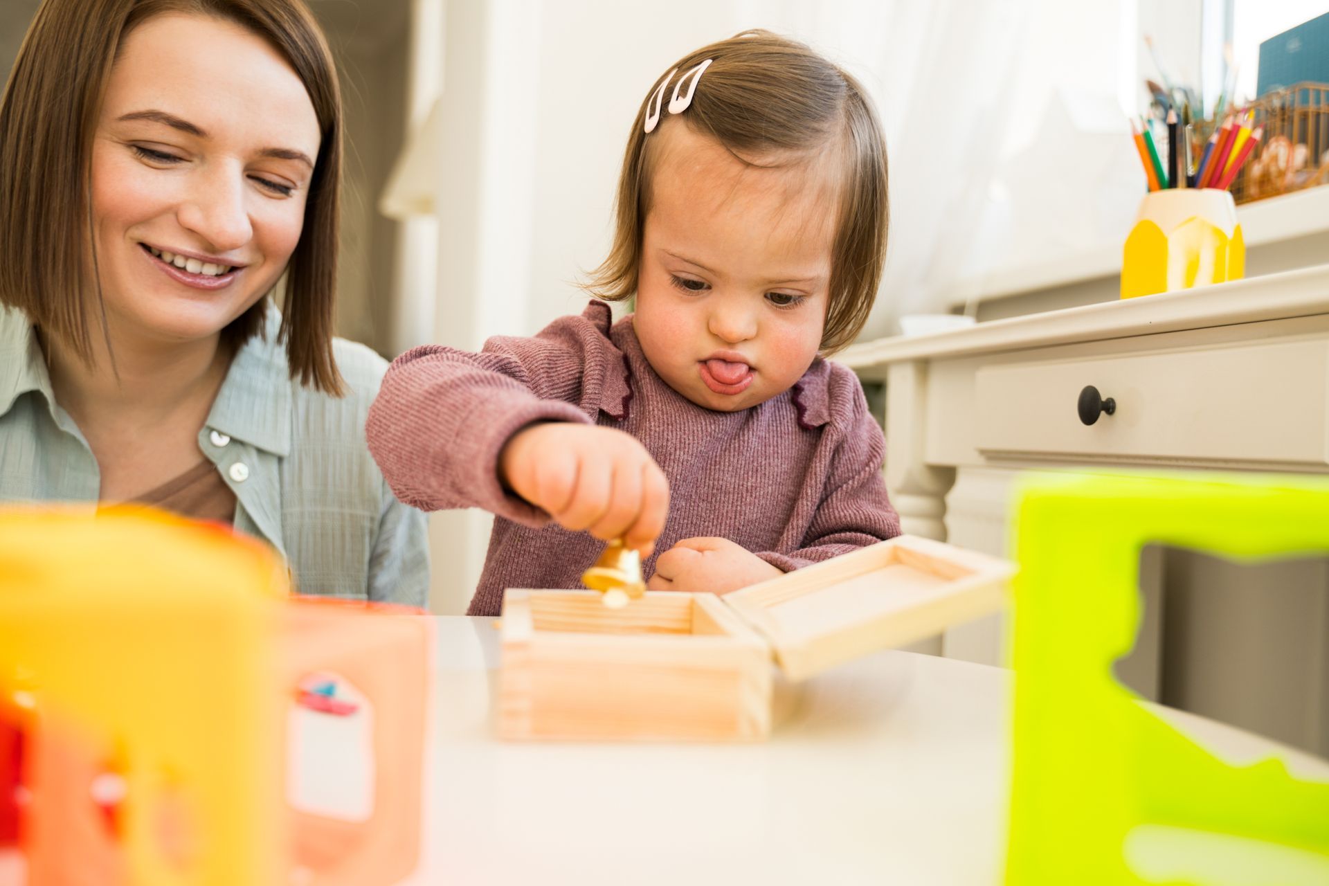 Woman and toddler playing with wooden blocks at a table in a bright kitchen