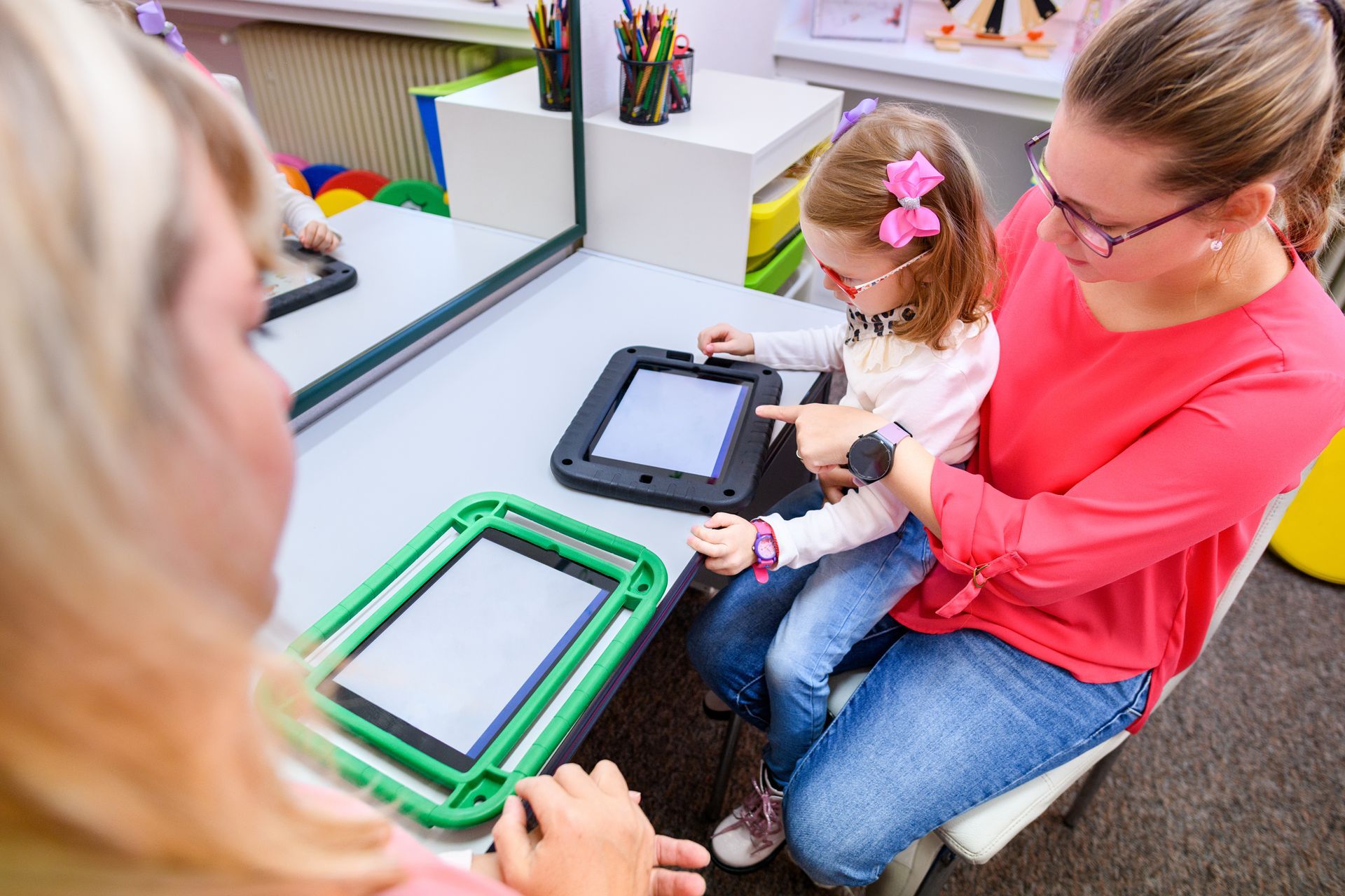 Adult and child assembling a colorful frame at a table in a classroom setting