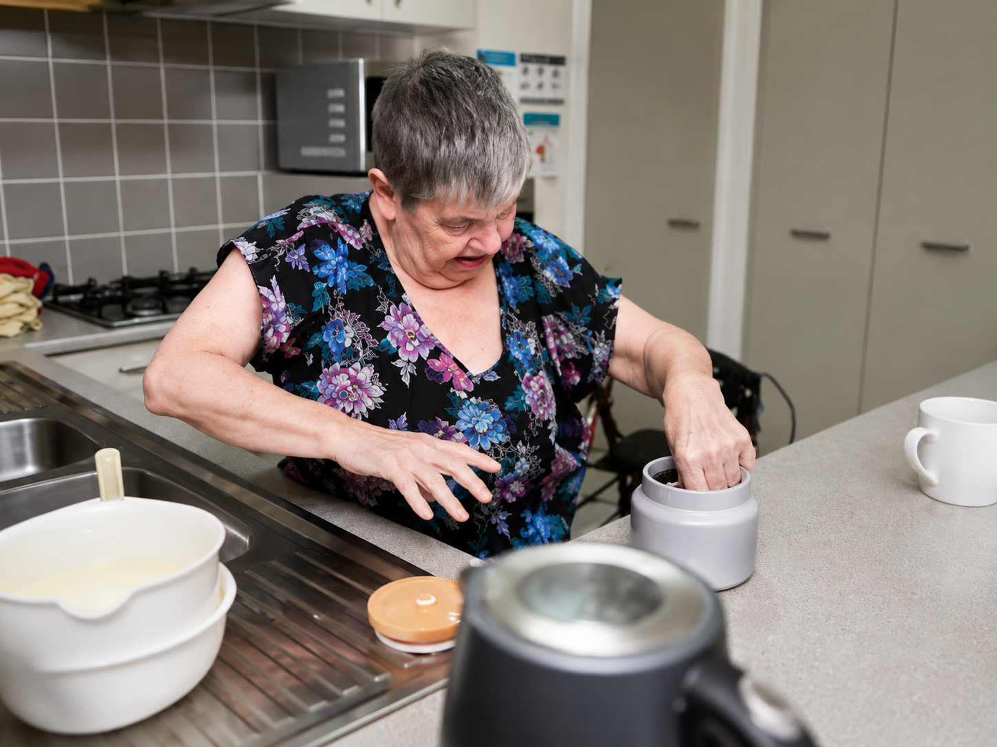 Woman using a hand blender at a kitchen counter, stirring ingredients in a white bowl