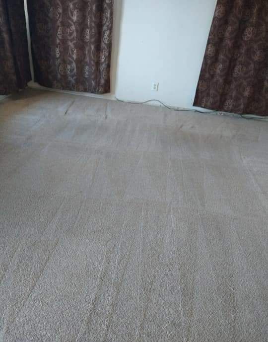 A large carpeted floor in a living room with brown curtains.