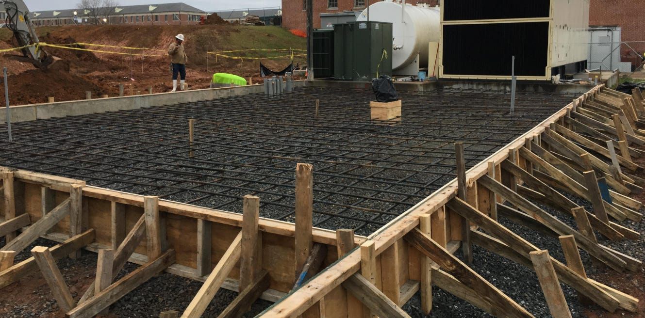 A construction worker wearing orange gloves is pouring concrete on a construction site.