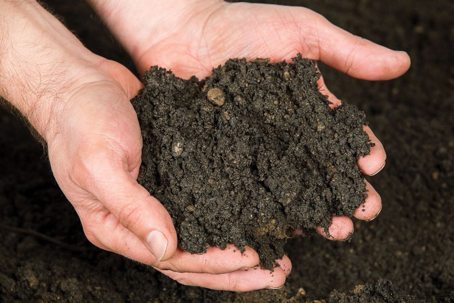 A construction worker wearing orange gloves is pouring concrete on a construction site.