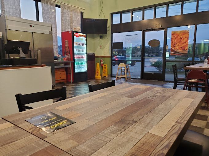 A wooden table in a restaurant with a menu on it.