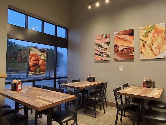 A restaurant with tables and chairs and pictures of food on the wall.