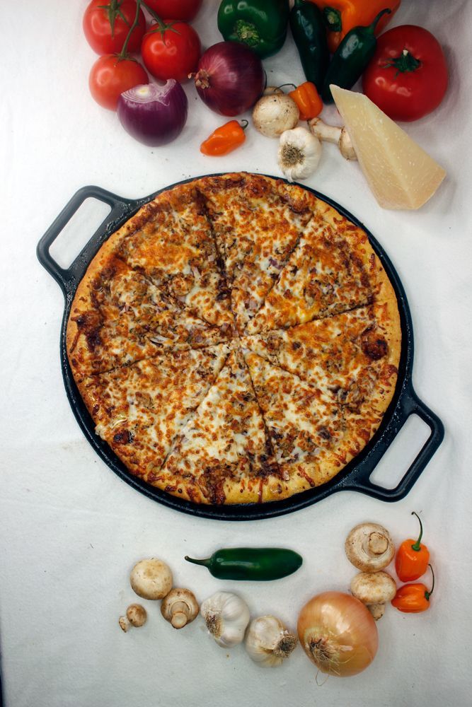 A pizza in a pan with vegetables around it