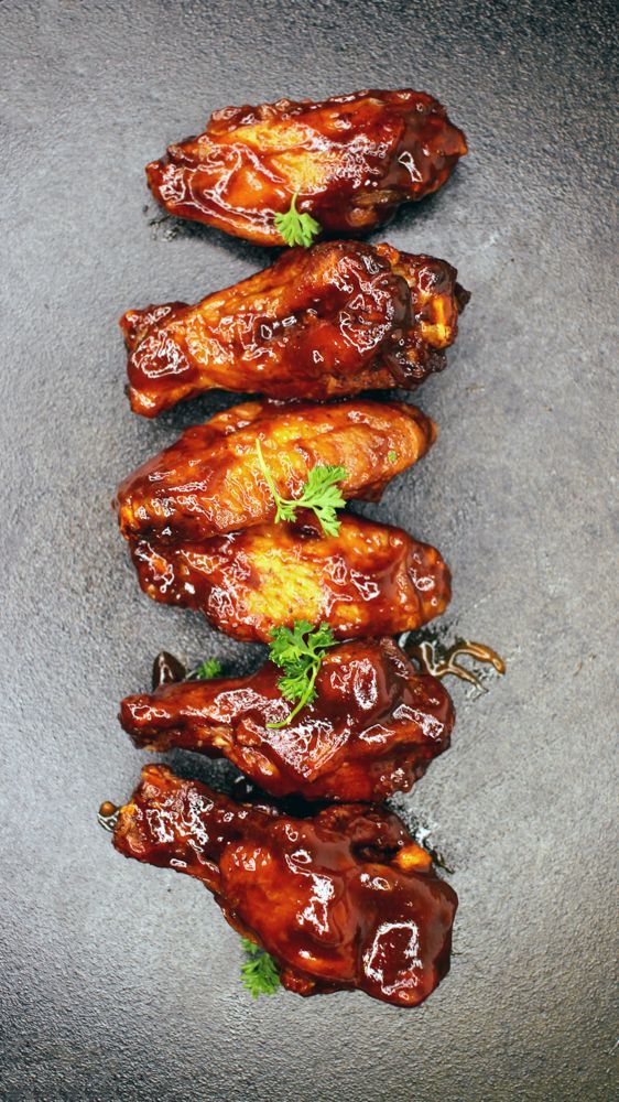 A close up of a plate of chicken wings on a table.