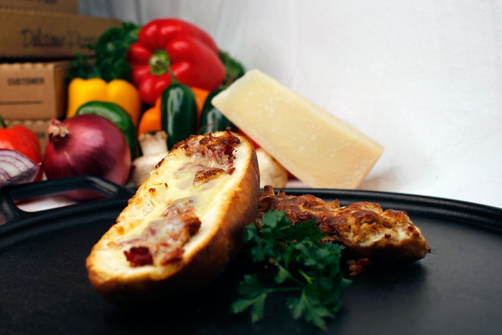 A slice of bread is on a black plate with vegetables in the background