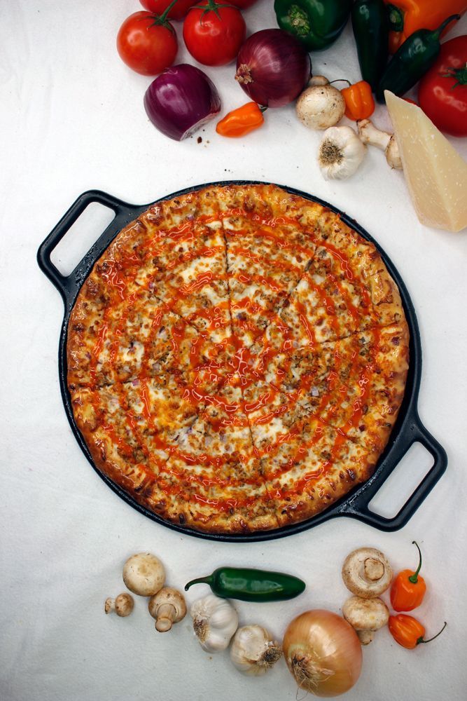 A pizza in a pan with vegetables around it