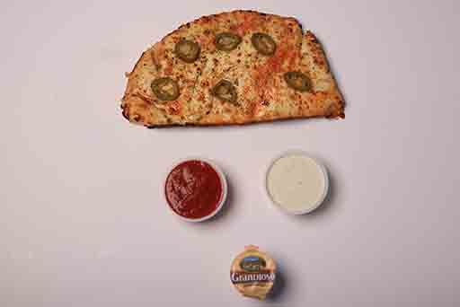 A pizza with ketchup and mayonnaise on a white surface.