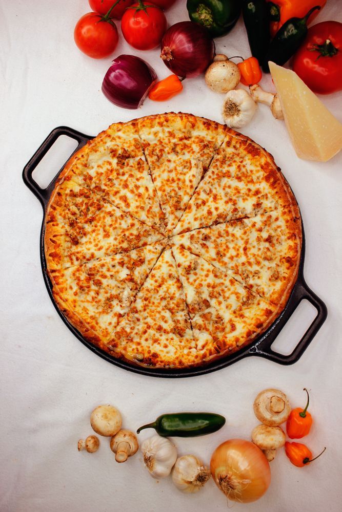 A pizza is sitting on a pan surrounded by vegetables.