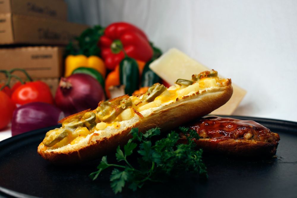 A close up of a sandwich on a plate with vegetables in the background
