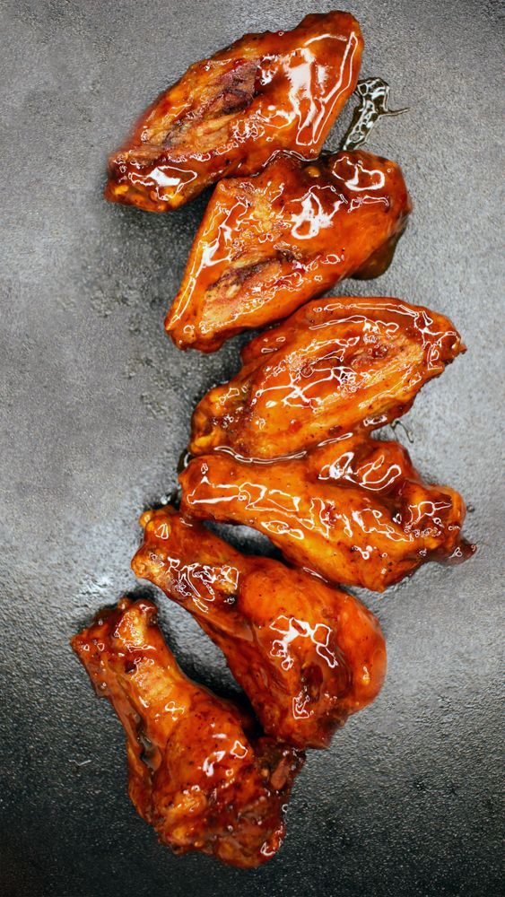 A bunch of chicken wings are sitting on top of each other on a table.