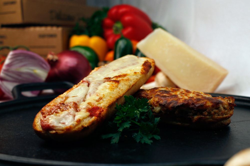 A close up of a pizza sandwich on a plate with vegetables in the background.