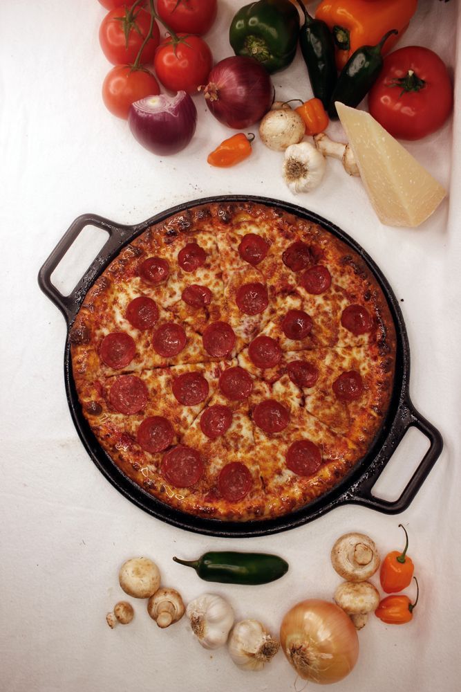 A pepperoni pizza in a pan surrounded by vegetables
