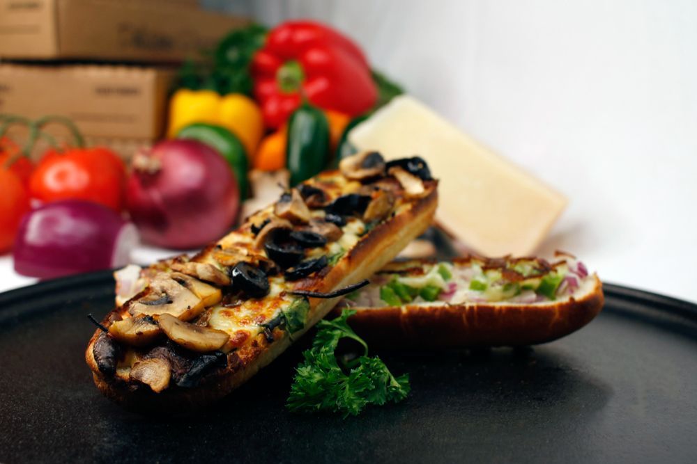 A sandwich with mushrooms and olives on a black plate