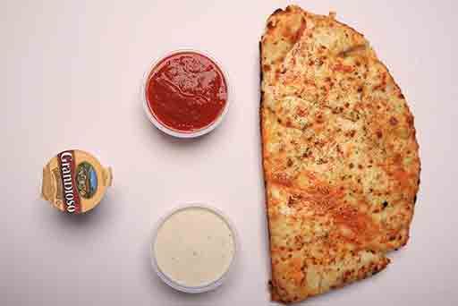 A pizza is sitting on a table next to sauces.