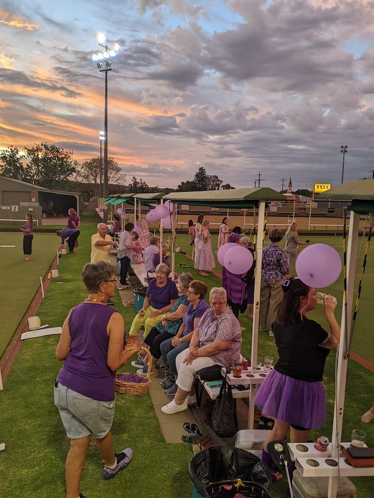 A Group Of People Are Sitting In A Field With Purple Balloons — Inverell Sporties in Inverell, NSW