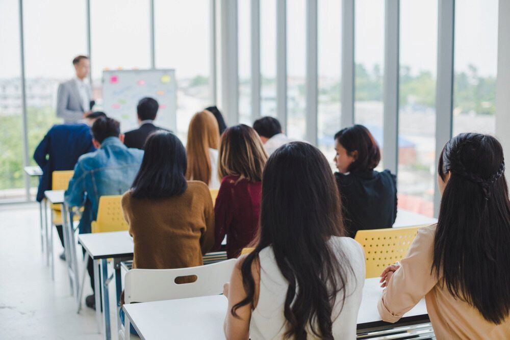 A Group Of People Are Sitting At Desks In A Classroom — Inverell Sporties in Inverell, NSW