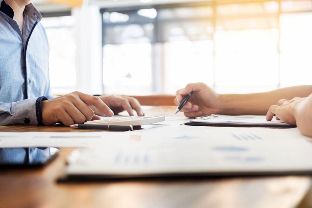 Two People Are Sitting At A Table Using A Calculator And A Pen — Inverell Sporties in Inverell, NSW