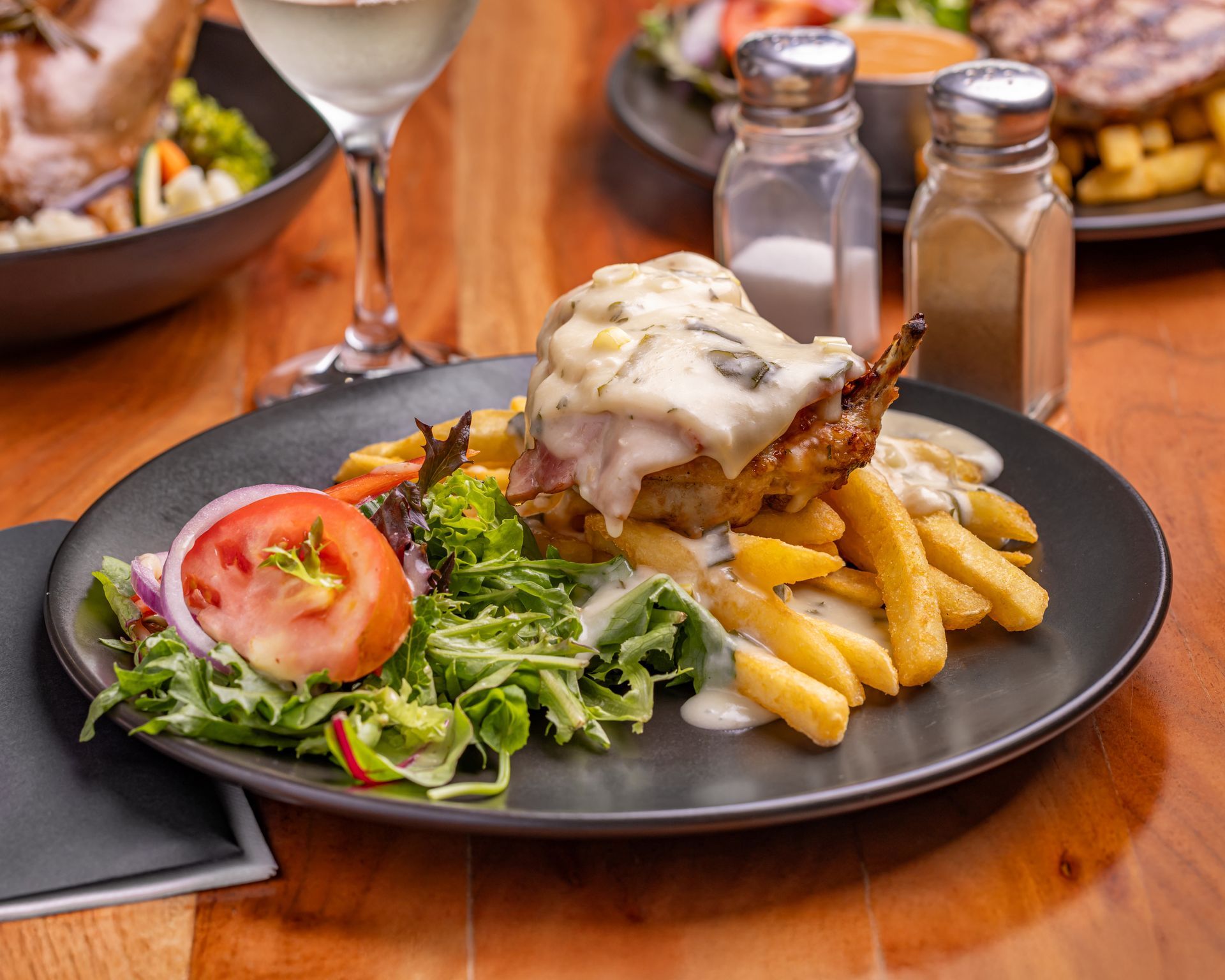 Plate of chicken dish with fries, salad, and creamy sauce — Inverell Sporties in Inverell, NSW