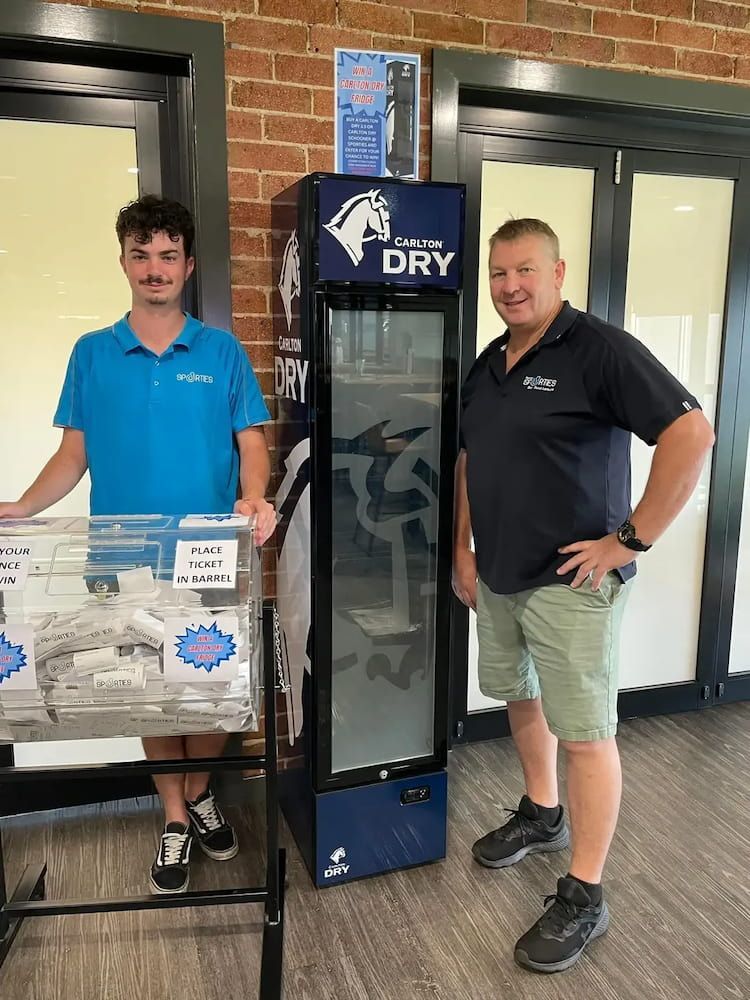 Two Men Are Standing Next To A Cooler In A Room — Inverell Sporties in Inverell, NSW
