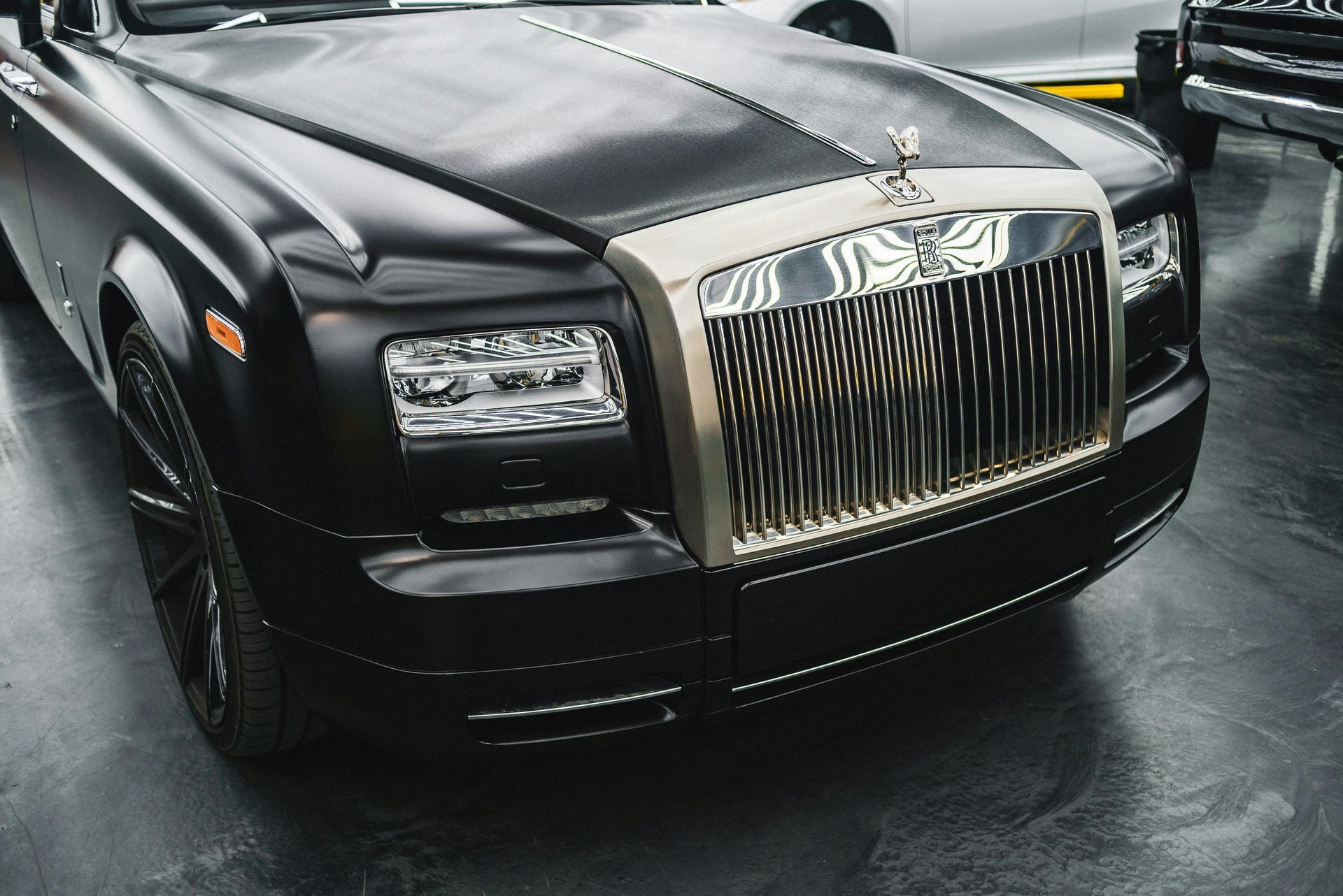 A black rolls royce is parked in a garage.