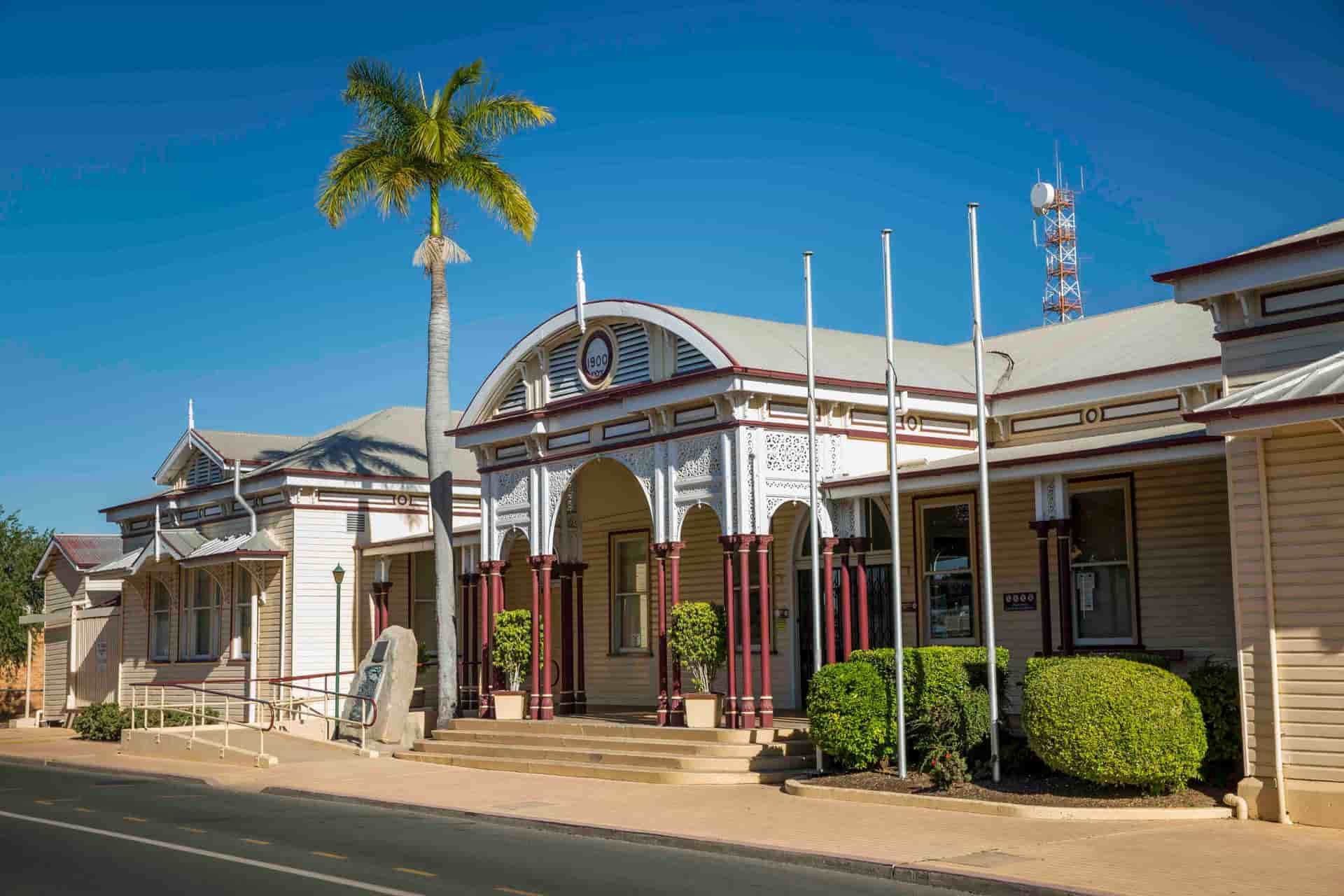A Large White Building With A Palm Tree In Front Of It — Mackay Septic Pumping In Bowen, QLD