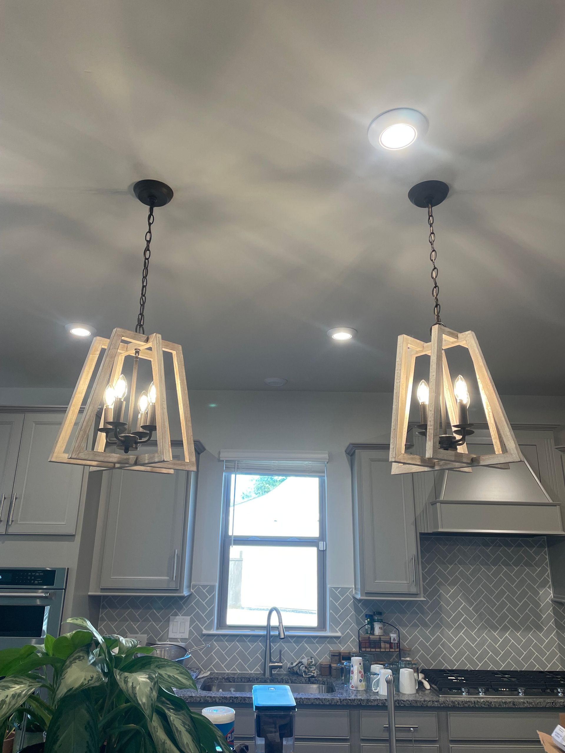 Two light fixtures hang above a kitchen island with cabinets and a window.