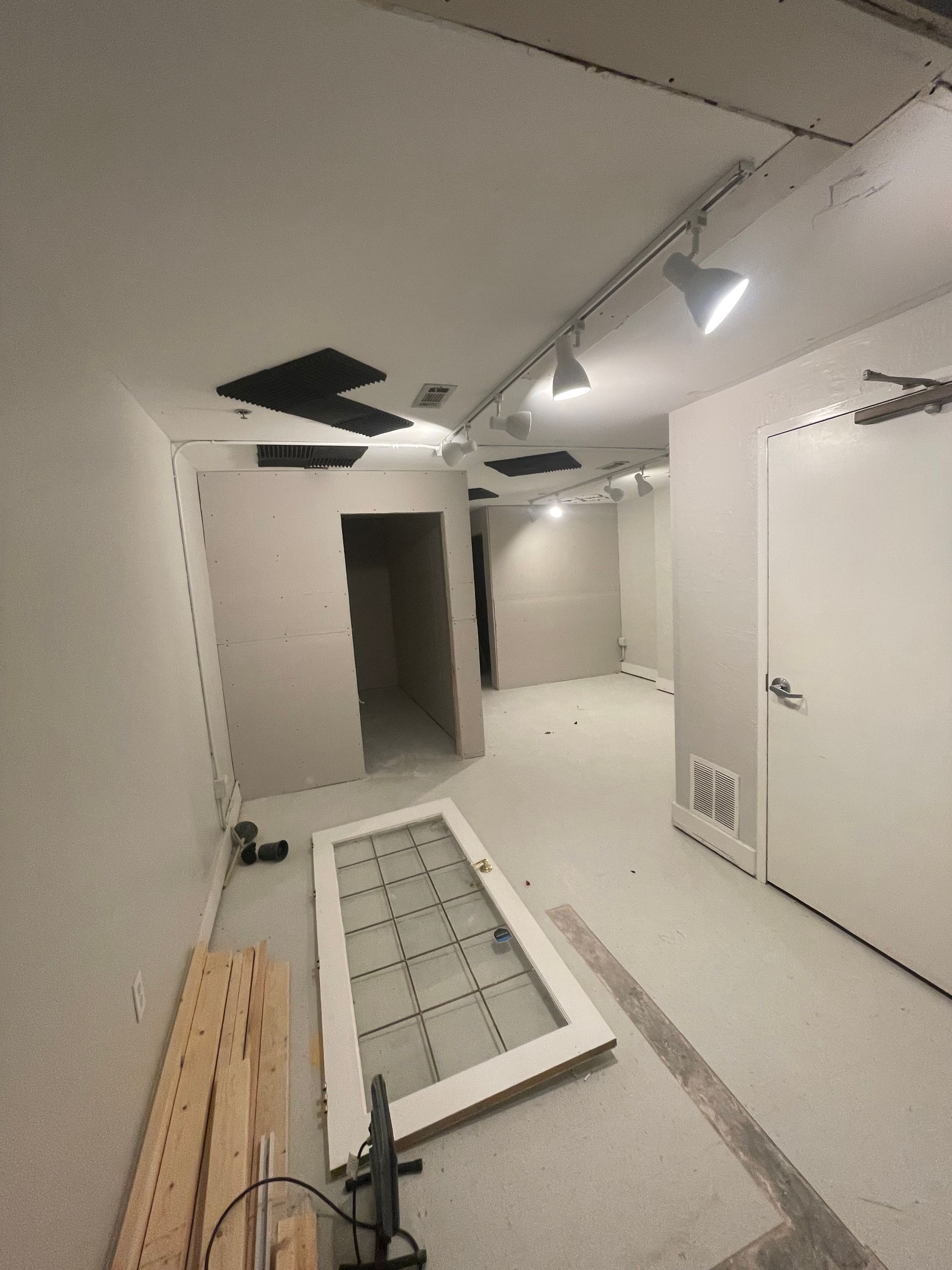 Interior room under construction, featuring white walls, open doorways, and a partially installed glass door. Interior room under construction, featuring white walls, open doorways, and a partially installed glass door.