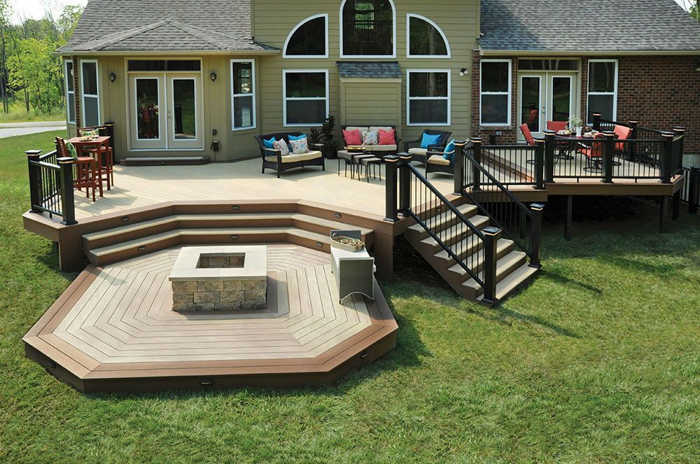 A large deck with stairs and a fire pit in front of a house.