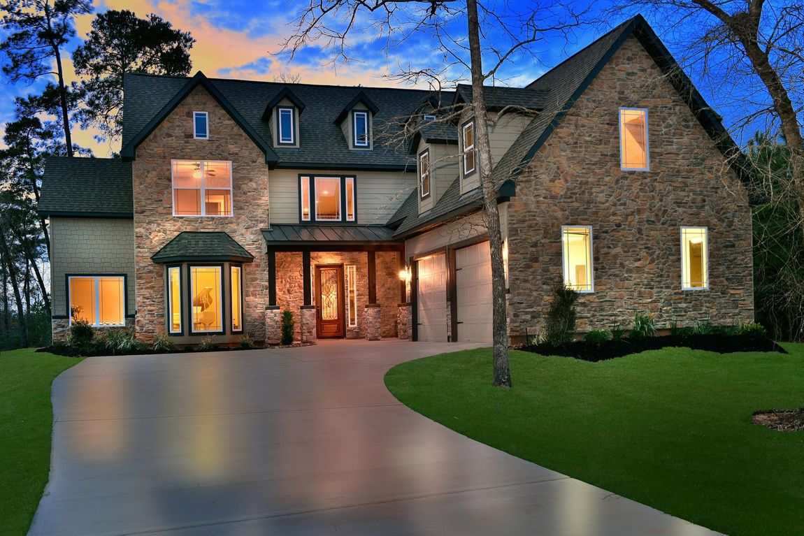 A large house with a lot of windows and a large driveway is lit up at night.