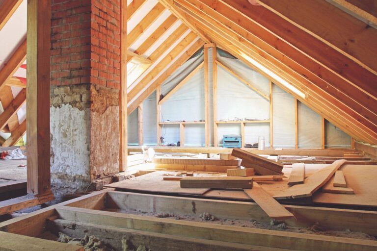 An attic under construction with wooden beams and a brick chimney.