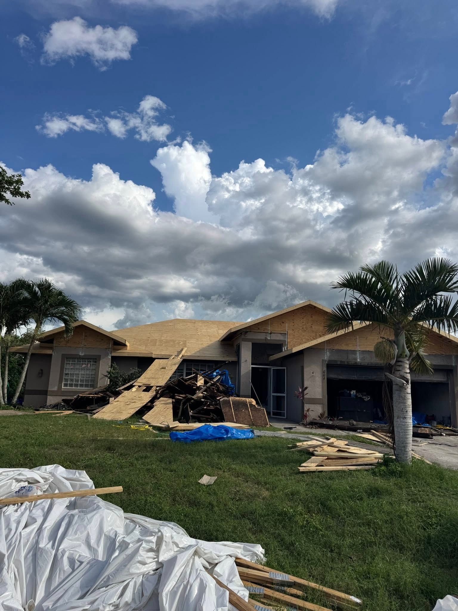 House under construction with exposed roof beams, garage, and blue sky.