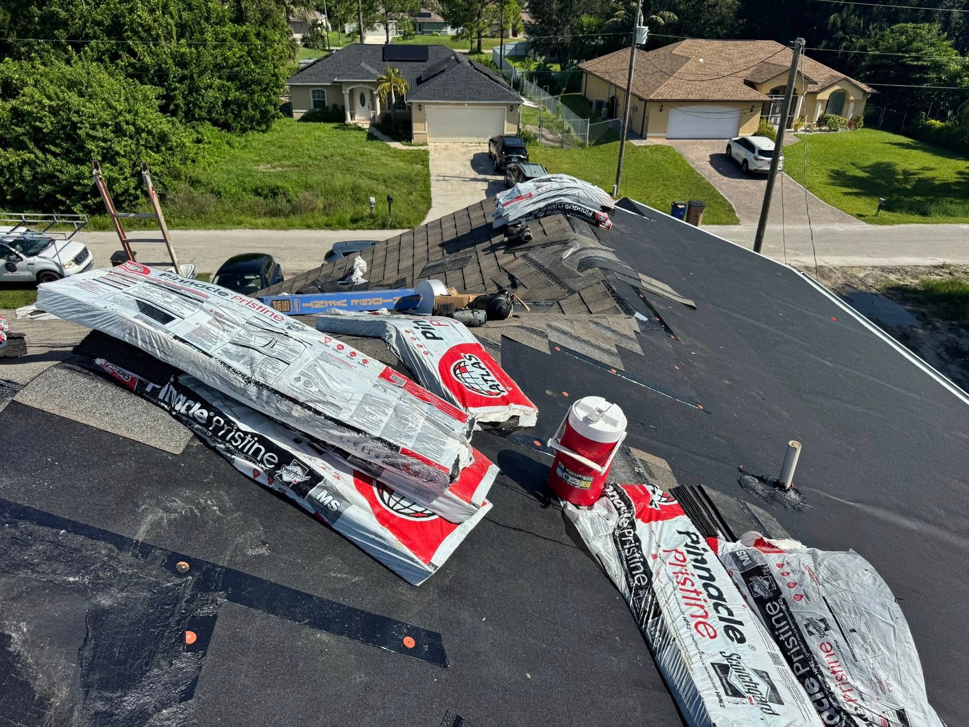 Roofing materials on a house roof undergoing repair; shingles, and supplies are visible.