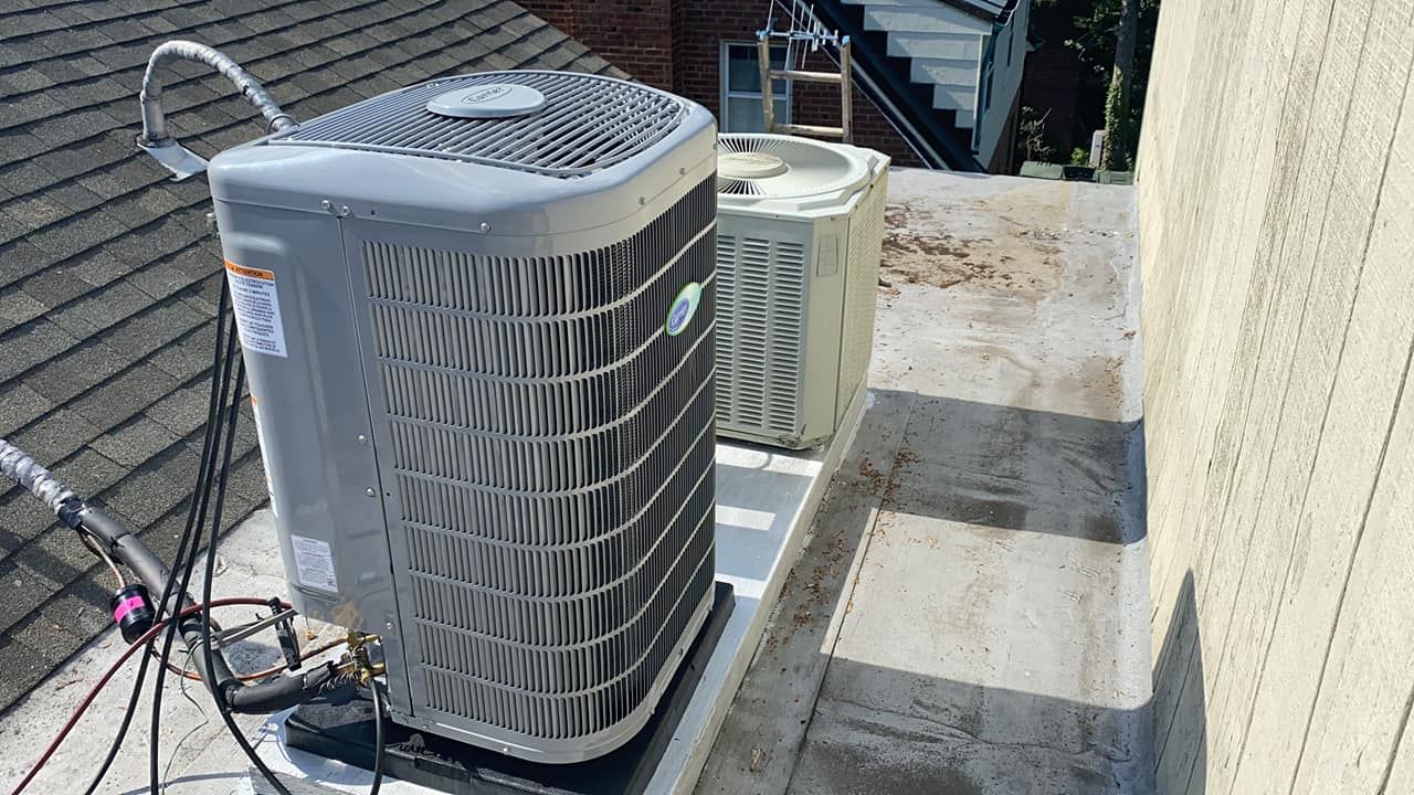 A couple of air conditioners are sitting on top of a roof.