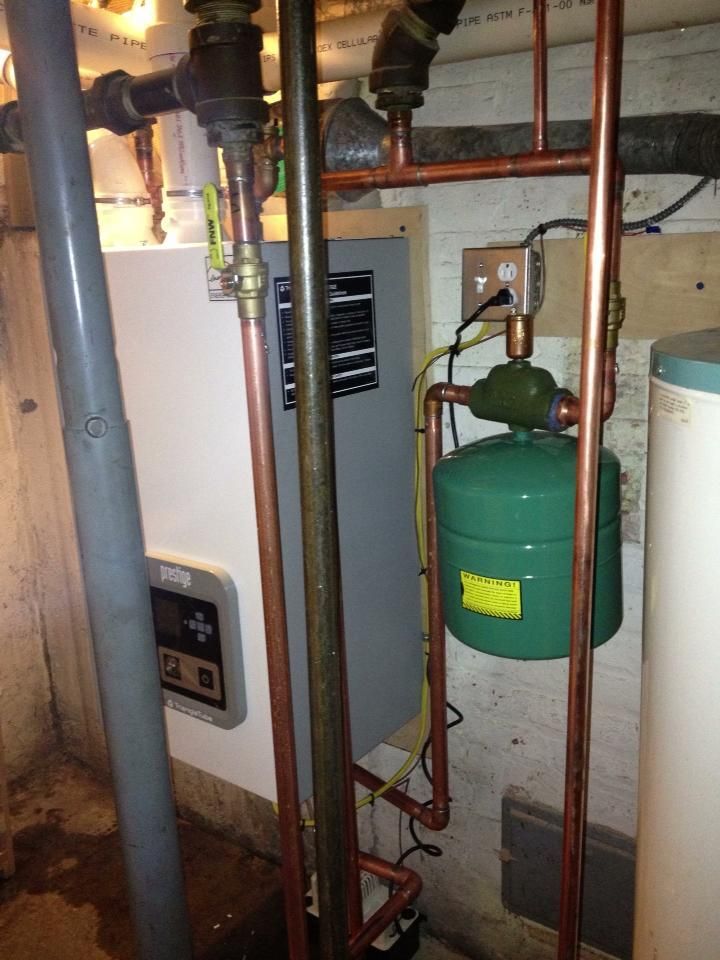 A boiler with copper pipes and a green tank attached to it