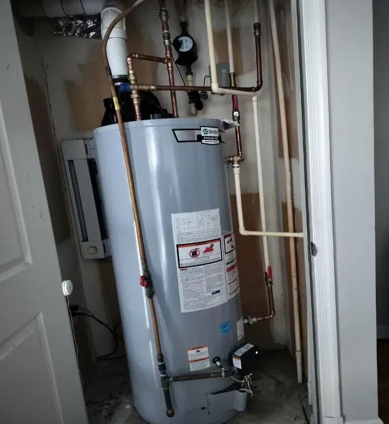 A water heater is sitting in a room next to a door