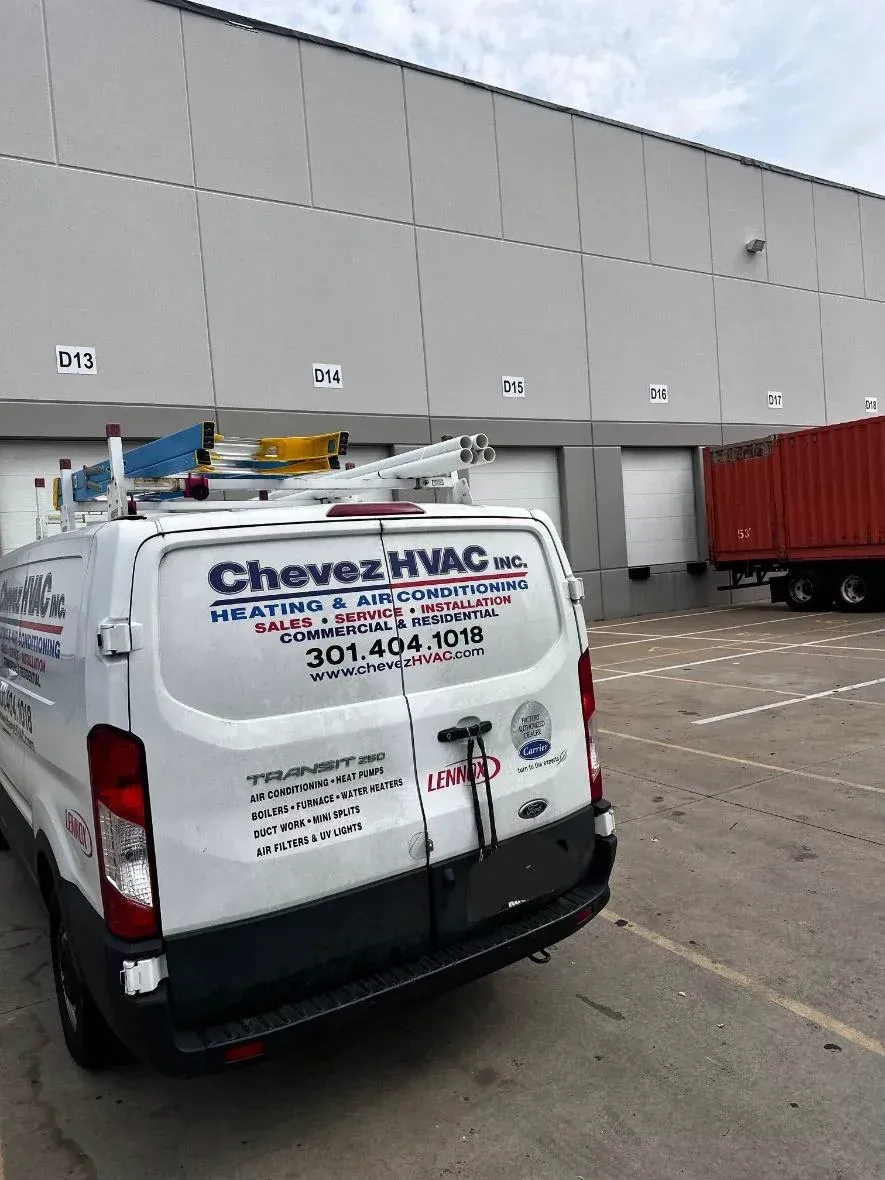 A white van is parked in a parking lot in front of a building.