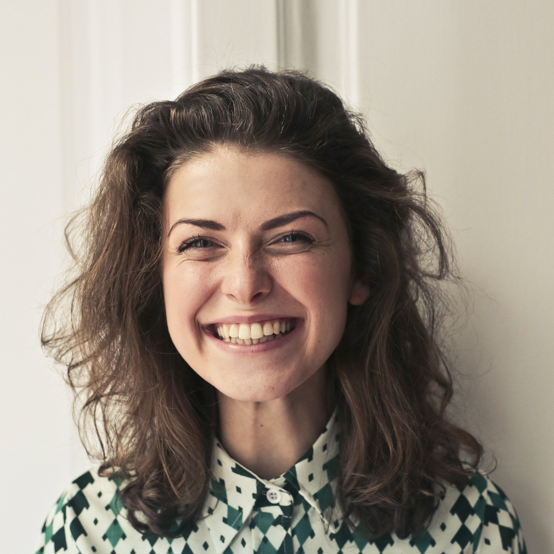 A woman wearing a green and white shirt is smiling