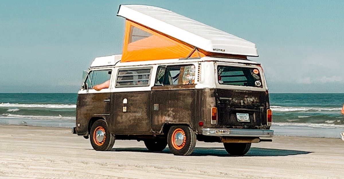 A camper van is parked on the beach next to the ocean.