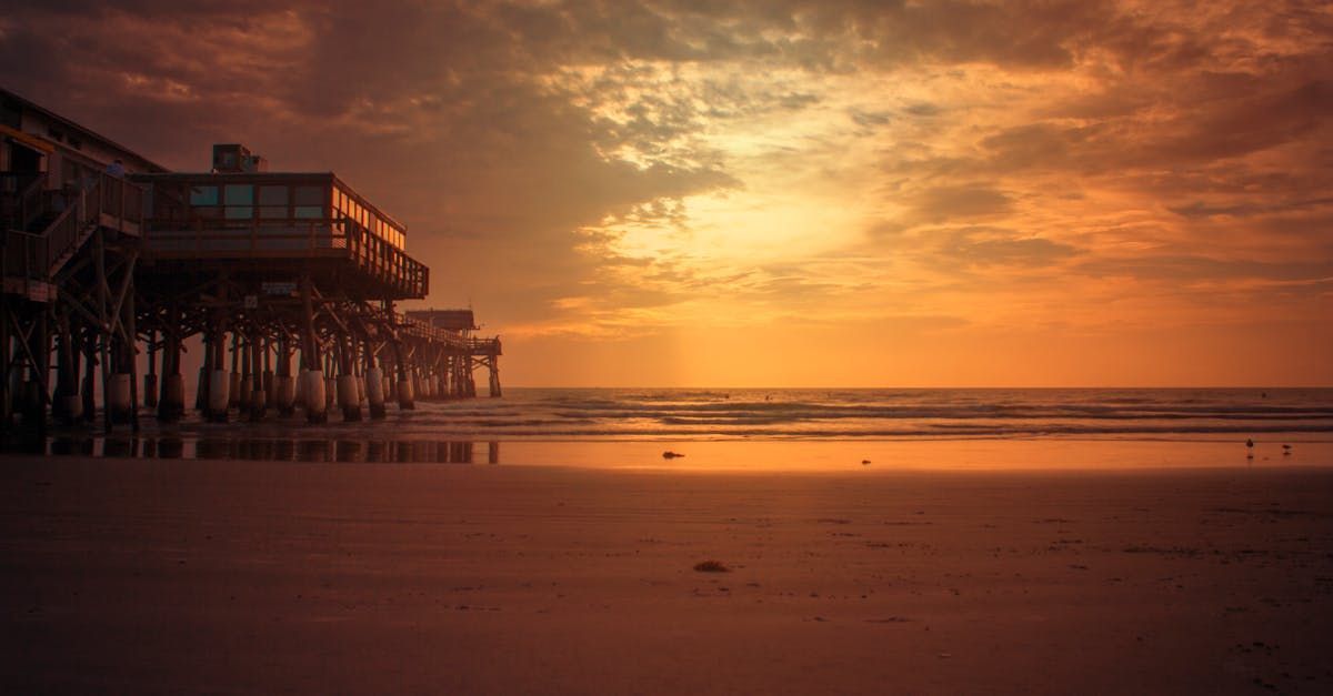 A pier on stilts overlooking the ocean at sunset.
