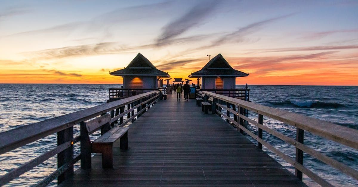 A pier leading into the ocean at sunset.