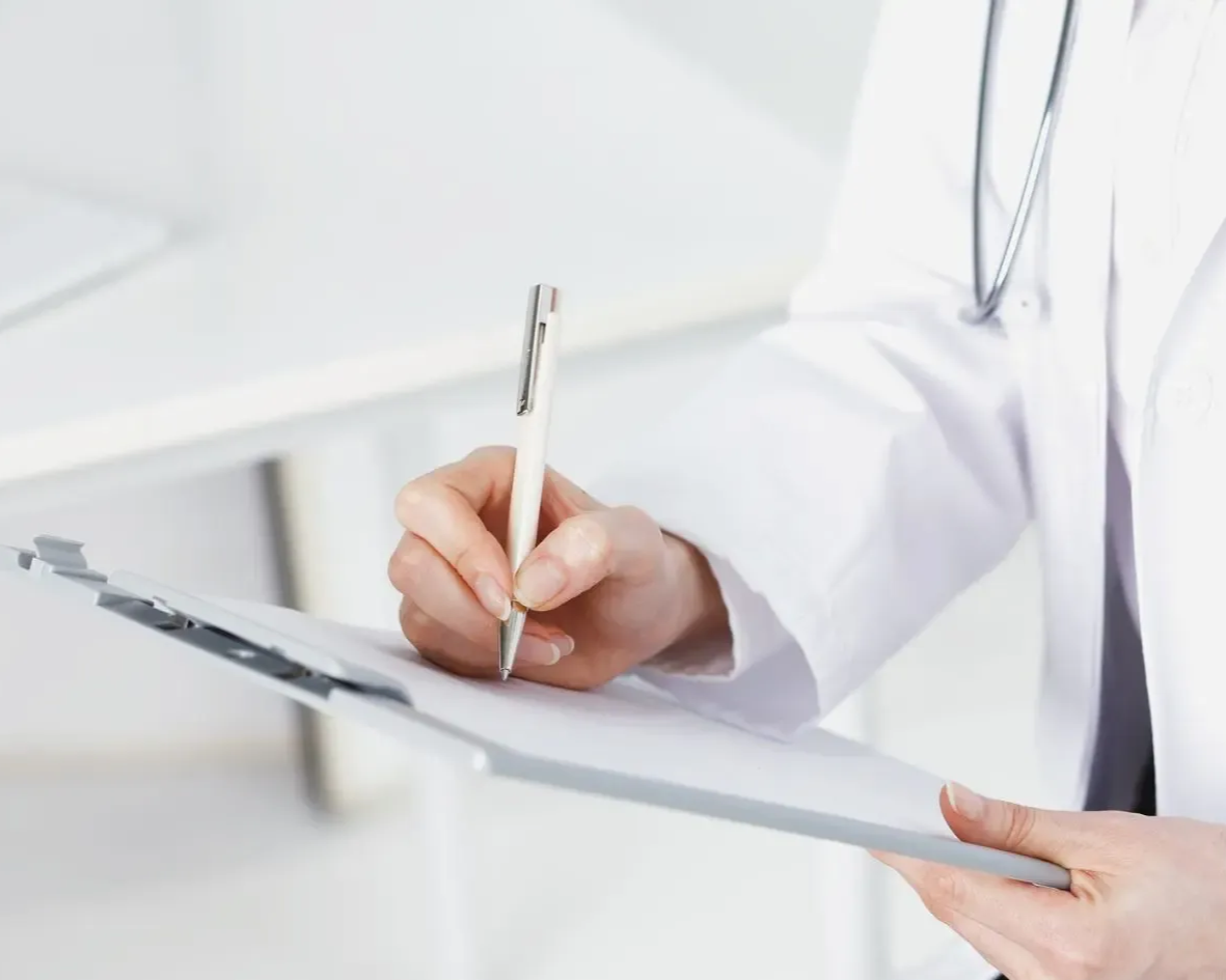 Person in pink sweatshirt, hands framing midsection. Green background.