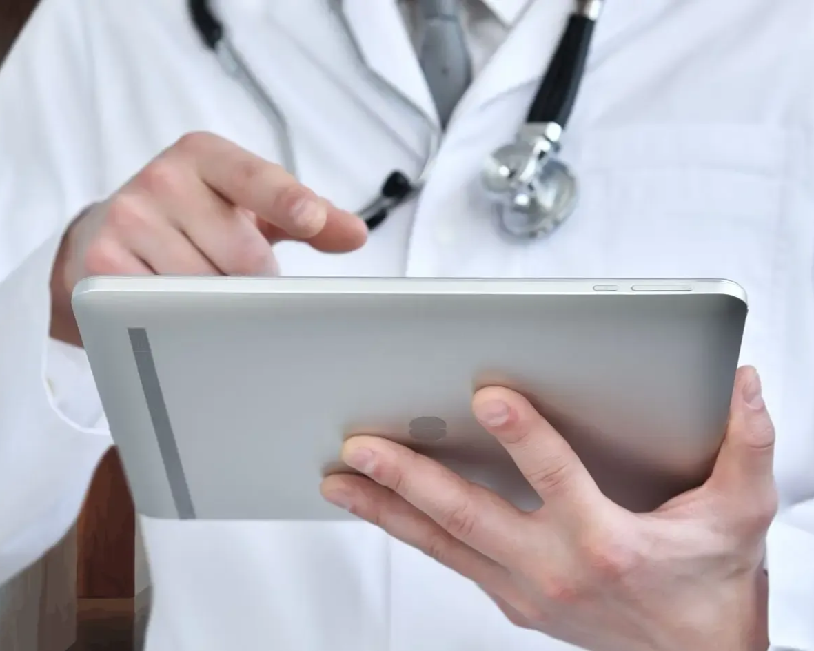 Person wearing pink shirt holding their abdomen, likely in pain.