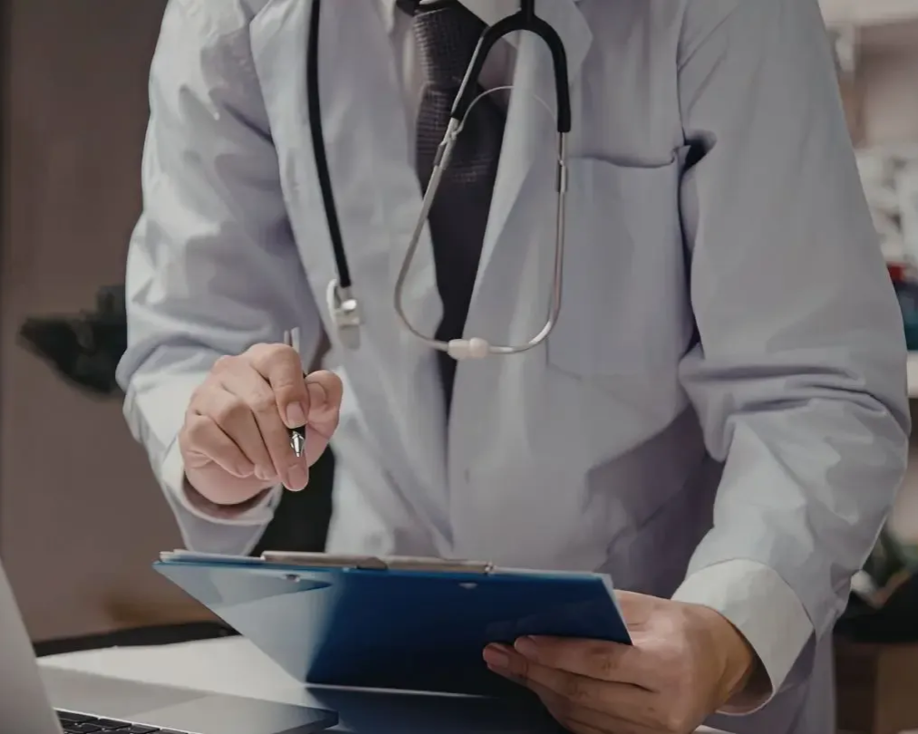 Person in pink sweatshirt, hands framing midsection. Green background.