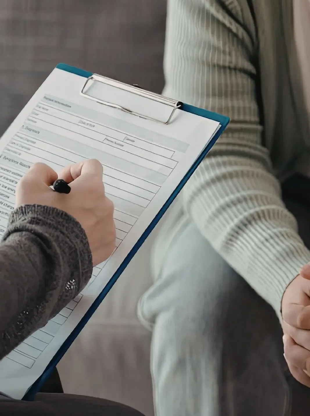 Doctor points to document on clipboard for a patient, likely discussing medical information.